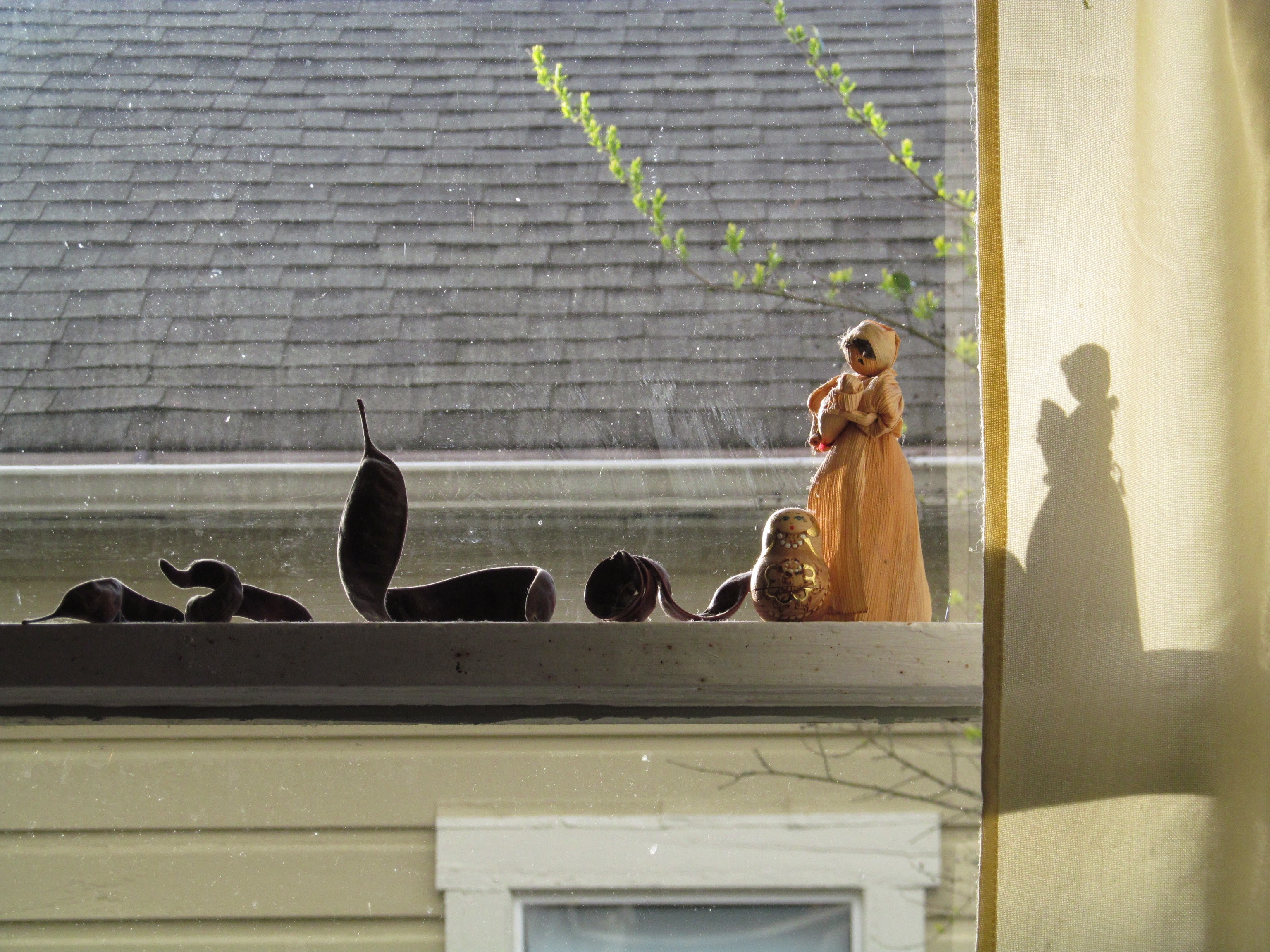Cornhusk doll on a window sill with seed pods